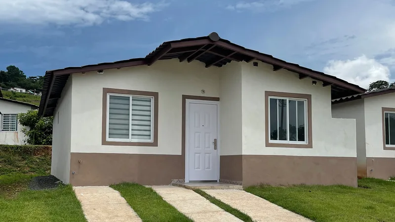 Fachada de casa unifamiliar terminada en Alamedas del Valle, con jardín frontal y acabados en blanco y marrón